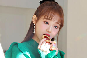 Chuu from the heart attack photoshoot. She is posing innocently and holding a mini jam tart to her lips.